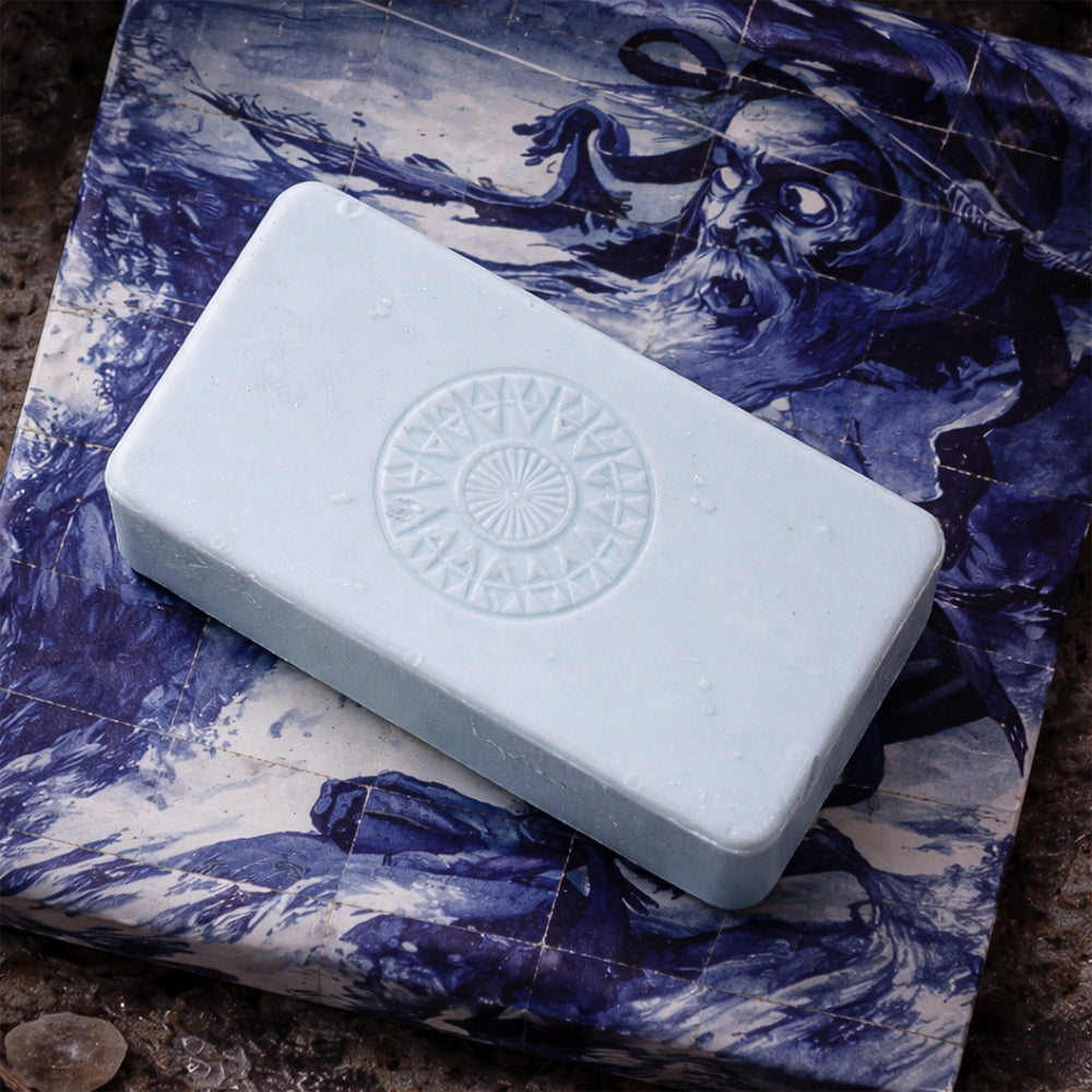 The Cabo das Tormentas 1488 – Cape of Storms soap from 100ml is a pale blue rectangular bar with a circular embossed pattern, resting on blue and white illustrated paper that evokes the fresh scent of marine accord.