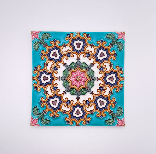Decorative ceiling tile featuring a symmetrical, colorful pattern with floral motifs in shades of green, pink, purple, and yellow, centered on a hand-crafted turquoise background by Tejo Shop.