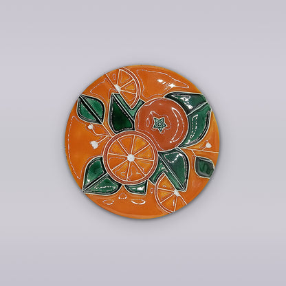 The Algarve Orange Blossom Ceramic Coaster by Miradouro Ceramics features a hand-painted design of oranges and green leaves on an orange background, inspired by classic Portuguese styles.