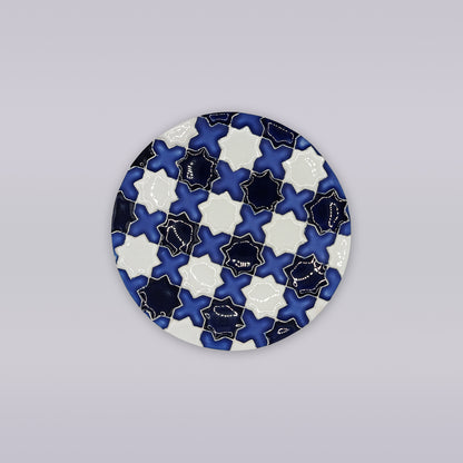 The Évora Star Azulejo Coaster by Miradouro Ceramics is a round ceramic piece featuring interlocking navy, white, and light blue star and cross patterns with gold outlines—ideal as handmade home decor.