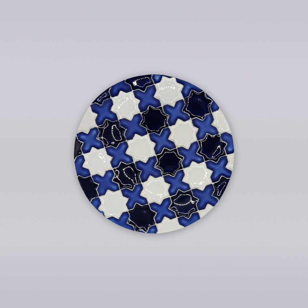 The Évora Star Azulejo Coaster by Miradouro Ceramics features a round Portuguese ceramic design with interlocking navy blue, white, and black star tiles—ideal for adding handmade azulejo style to your decor.