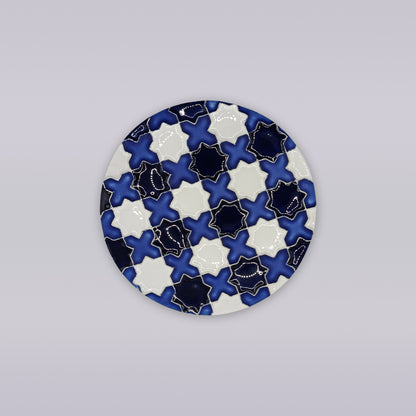 The Évora Star Azulejo Coaster by Miradouro Ceramics features a round Portuguese ceramic design with interlocking navy blue, white, and black star tiles—ideal for adding handmade azulejo style to your decor.
