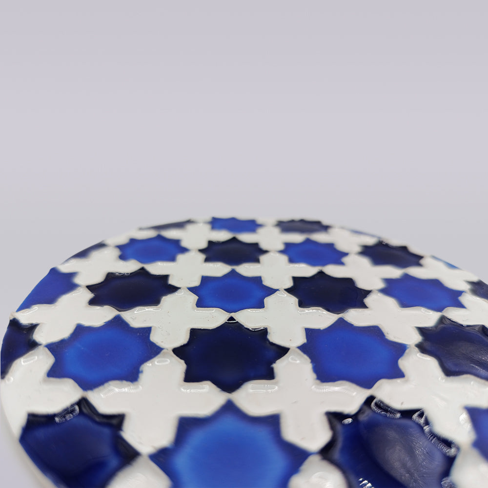 Close-up of the Heritage Blue Star Mosaic Coaster by Miradouro Ceramics, featuring blue star and white cross shapes in a geometric azulejo-inspired pattern, set against a plain light gray background.