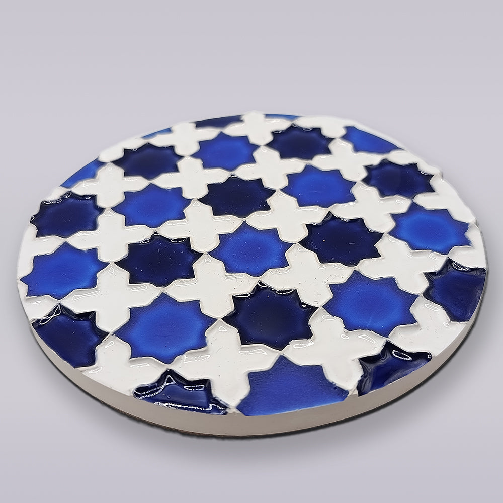 The Heritage Blue Star Mosaic Coaster by Miradouro Ceramics is a round Portuguese ceramic coaster featuring a geometric star pattern in white and blue shades, inspired by hand-painted azulejo tiles on a light gray background.