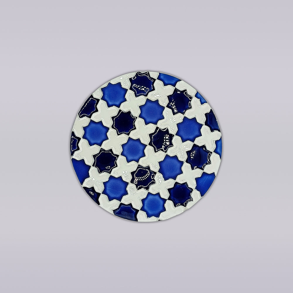 The Heritage Blue Star Mosaic Coaster by Miradouro Ceramics features interlocking white and blue star shapes on a light gray background, inspired by azulejo designs, with blue accents and detailed white patterns evocative of Portuguese ceramics.