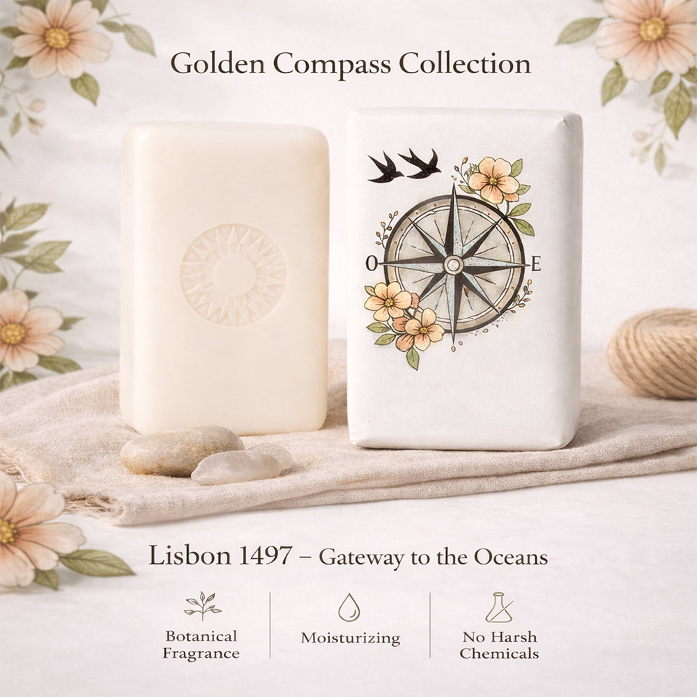 Two decorative soap bars from 100ml’s Lisbon 1497 – Gateway to the Oceans line, one embossed and one with compass and floral designs, rest on a floral cloth. They offer botanical and marine scents, moisturizing benefits, and contain no harsh chemicals.