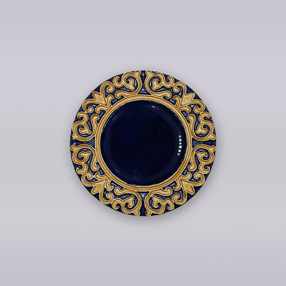 The Manuel I Royal Crest Ceramic Coaster by Miradouro Ceramics is a round, dark blue Portuguese piece with a gold, Manueline-inspired patterned border, shown against a light gray background.