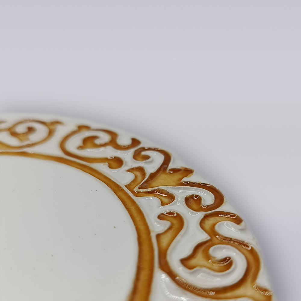 Close-up of the Manueline Golden Crest Ceramic Coaster by Miradouro Ceramics, featuring an ornate, raised golden-brown border inspired by Portuguese design, on a plain light background.
