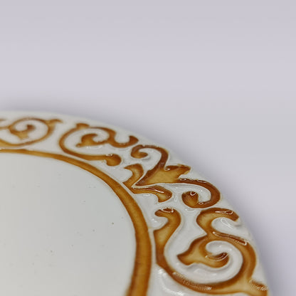 Close-up of the Manueline Golden Crest Ceramic Coaster by Miradouro Ceramics, featuring an ornate, raised golden-brown border inspired by Portuguese design, on a plain light background.