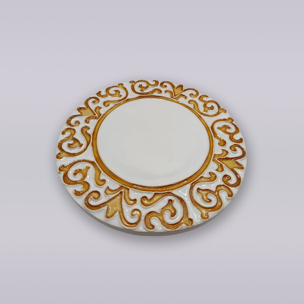 The Manueline Golden Crest Ceramic Coaster by Miradouro Ceramics features an ornate gold pattern inspired by Portuguese décor, set against a white base and shown on a plain light background.