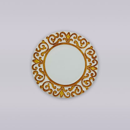 The Manueline Golden Crest Ceramic Coaster by Miradouro Ceramics features a round white design with an ornate gold and brown border of symmetrical swirls, inspired by Portuguese decor, displayed on a plain light gray background.