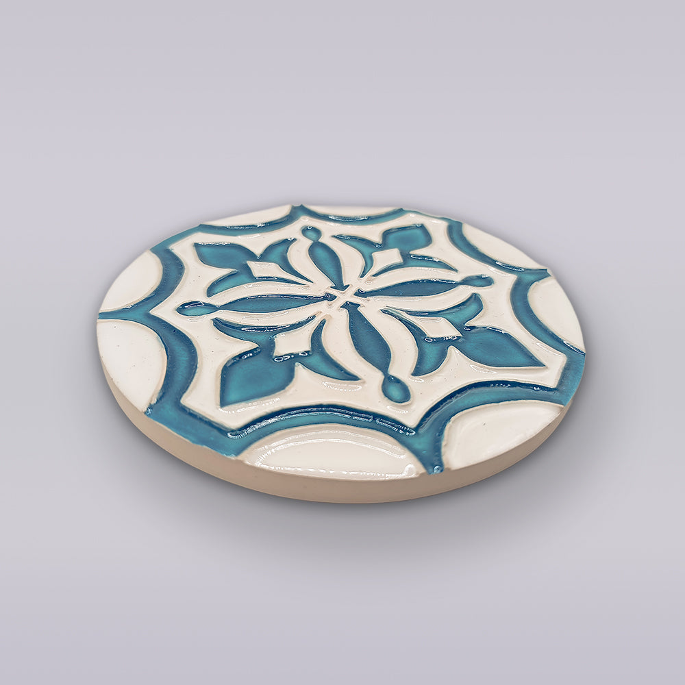 The Portuguese Flor-de-Lis Tile – Atlantic Edition by Miradouro Ceramics features a raised blue and white floral-cross motif on ceramic—a charming decorative accent displayed against a light gray background.