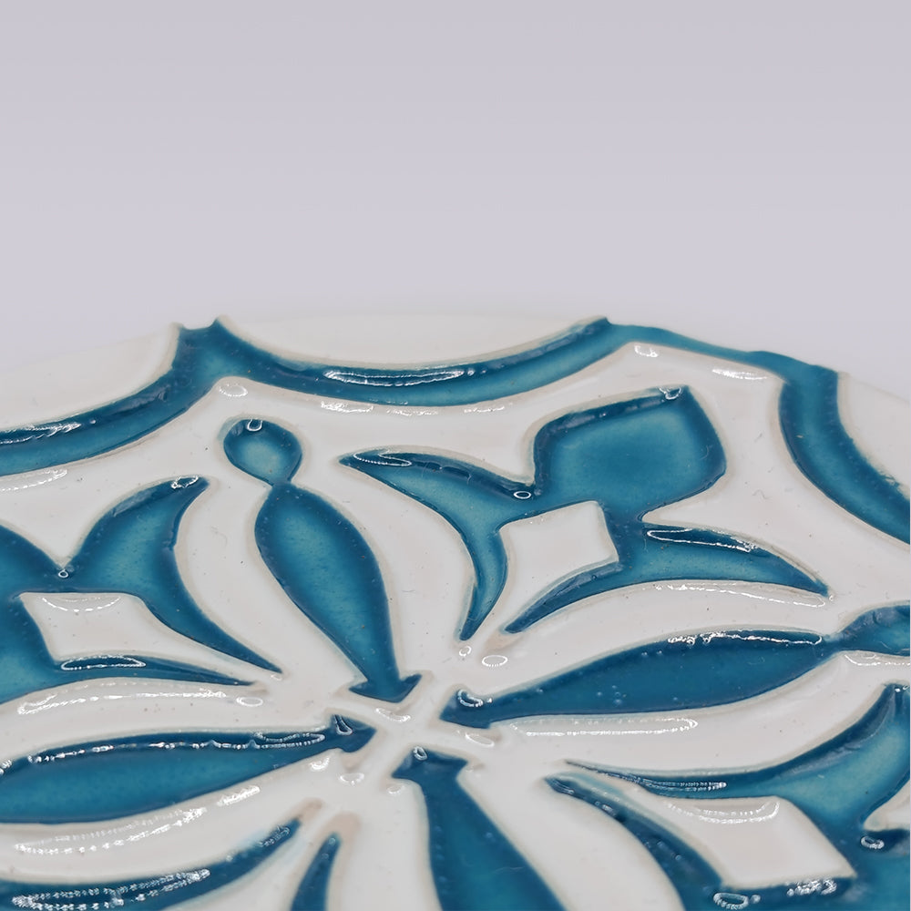A close-up of the Miradouro Ceramics Portuguese Flor-de-Lis Tile – Atlantic Edition, showcasing its raised blue and white floral-cross motif against a simple light background.