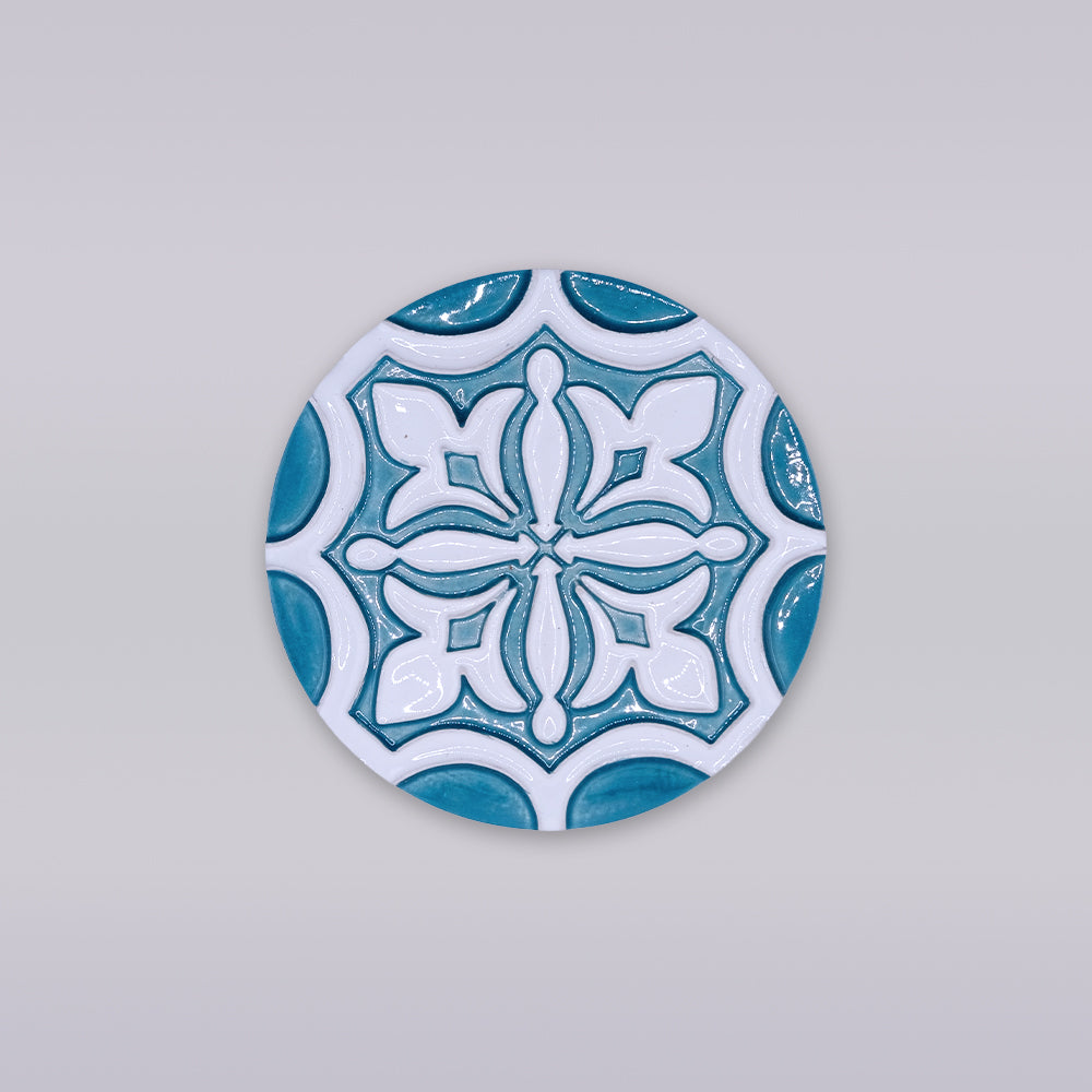 The Rosacrux Atlântica by Miradouro Ceramics is a round ceramic tile with a blue and white geometric design on light gray, ideal as a stylish decorative coaster for any setting.