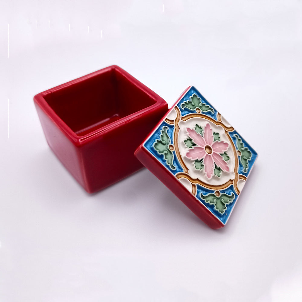 A small, open red Berlengas Island Ceramic Box by Tejo Shop with a detached lid positioned next to it. The lid features a colorful floral and geometric pattern with pink, green, blue, and yellow elements. The background is plain white, showcasing superb craftsmanship.