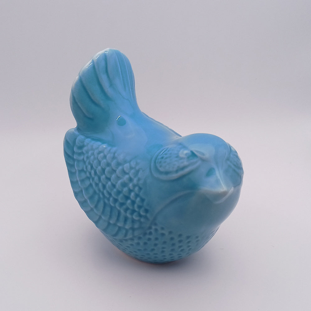 Crafted by Tejo Shop, the Ceramic Bird Figurine is a small, handmade piece adorned with a glossy, light blue finish. It showcases intricate, textured patterns on its wings, tail, and body. Perfect for home decor, it stands gracefully against a white background.