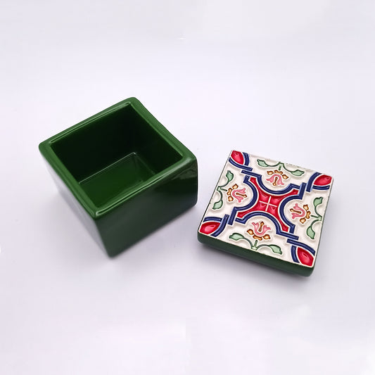 A small, square green ceramic box known as the Estoril Ceramic Box by Tejo Shop with an ornate detachable lid lies open. The lid features an intricate mosaic-like design with red, green, and blue patterns, adding artistic elements to your home decor.