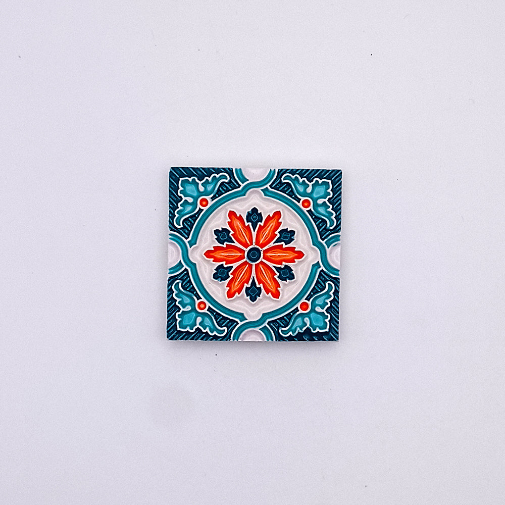 A decorative hand-made Portuguese ceramic tile featuring a vibrant red and orange floral design surrounded by blue accents on a white background, from Tejo Shop.