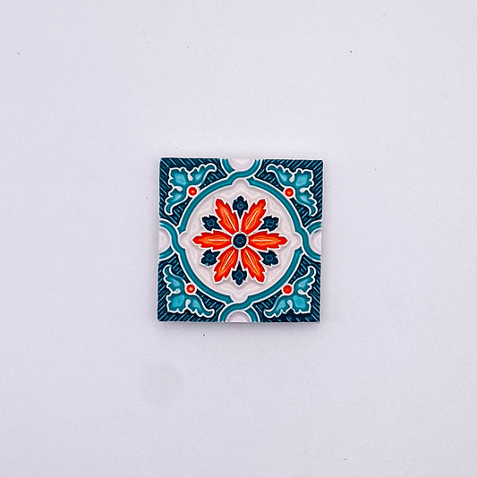 A decorative hand-made Portuguese ceramic tile featuring a vibrant red and orange floral design surrounded by blue accents on a white background, from Tejo Shop.