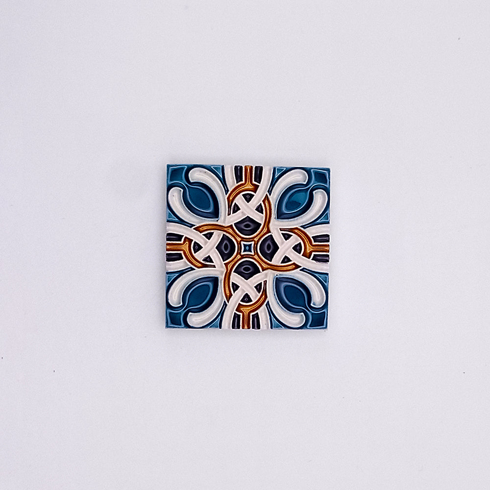 A decorative Hand Painted Portuguese Ceramic Tile from Tejo Shop featuring a symmetrical, geometric pattern with interlocking designs predominantly in blue, white, and dark red colors on a neutral background.