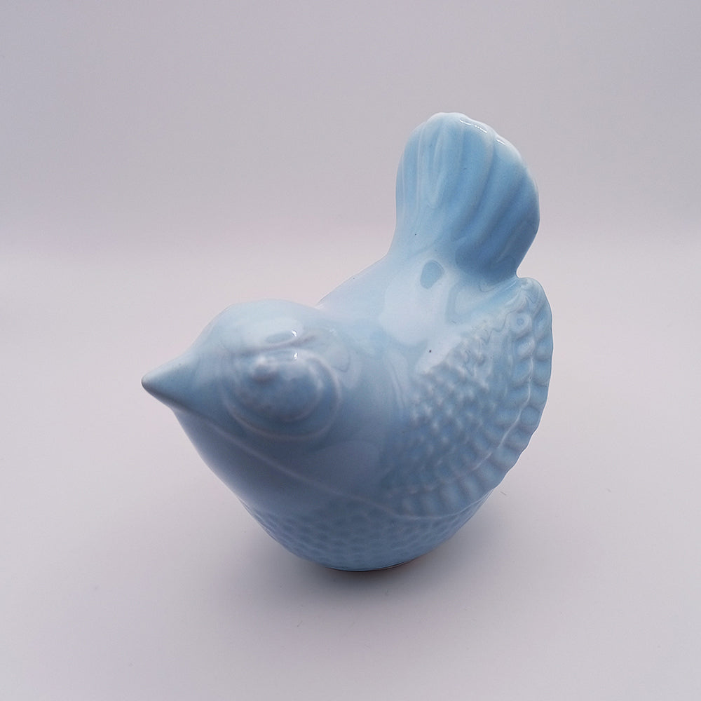 A small, handmade Ceramic Bird Figurine by Tejo Shop, featuring light blue ceramic with textured feathers and a smooth finish, is presented against a plain white background. Perfect as home decor, the bird sits upright and faces slightly to the left.