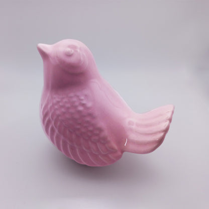 The Tejo Shop Ceramic Bird looking up Figurine, a small pink ceramic bird with intricate feather details and a smooth, glossy finish, is displayed against a plain background. This handmade figurine faces left with its beak slightly upward, making it an ideal piece for home decor.