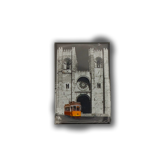 The New Jamp "Sé Patriarcal de Lisboa - Fridge Magnet" features a yellow Lisbon tram before the iconic twin-towered Lisbon Cathedral, set against a black and white backdrop—a perfect city keepsake.