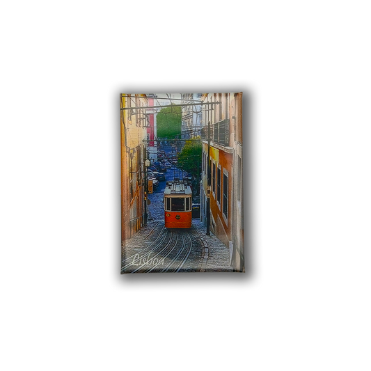 The Lisbon Tram - Fridge Magnet by New Jamp features a red tram going uphill between vibrant buildings in a narrow Lisbon street with greenery, and "Lisbon" written at the corner—making it a charming souvenir.