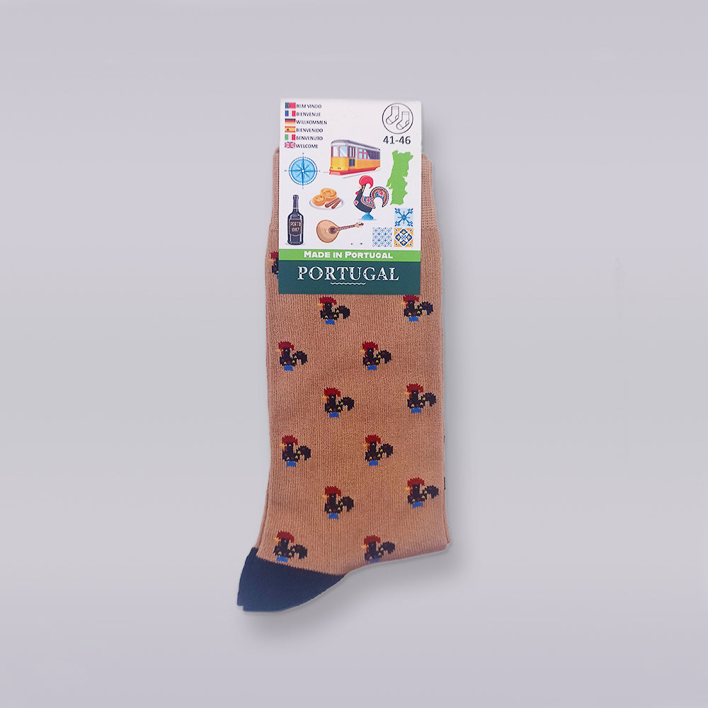 A single sock from Tejo Shop's "Socks - New Classic Barcelos Rooster Pattern" collection is displayed against a white background. The tan sock, crafted from high-quality cotton, features a dark blue toe and an intricate pattern of small, colorful Barcelos Roosters. The packaging label at the top indicates it is "Made in Portugal" and showcases various Portuguese symbols like trams, wine, and pastries.