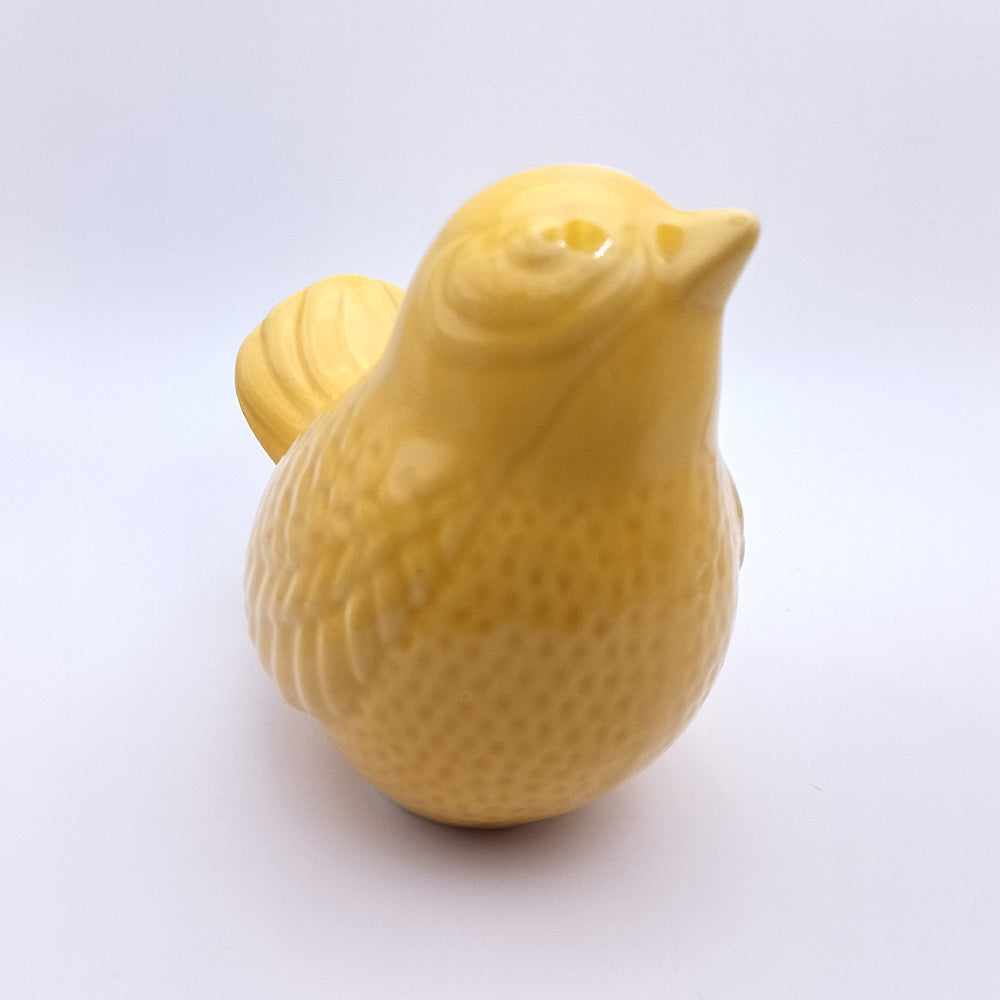 Introducing the Ceramic Bird Looking Up Figurine by Tejo Shop, a beautifully handmade ceramic yellow bird figurine. This charming piece features a textured surface, wide body, and an extended tail. Perfect for home decor, it is showcased against a plain white background.